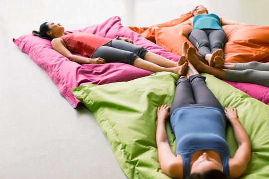 Women laying on cushions in restorative yoga gym studio