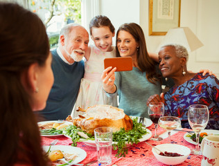 Multi-ethnic multi-generation family camera phone taking selfie at Christmas dinner table