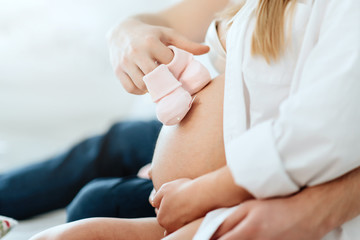 Baby shoes on a pregnant belly. Pregnant Woman With Her Husband
