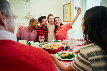 Multi-ethnic family camera phone taking selfie at Christmas dinner table