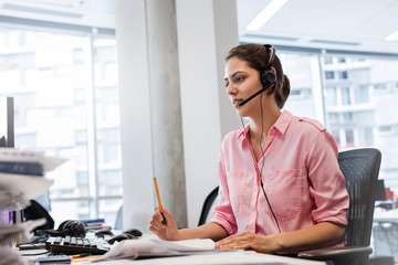 Businesswoman handsfree device talking on telephone at office desk