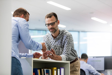Businessmen using cell phone in office