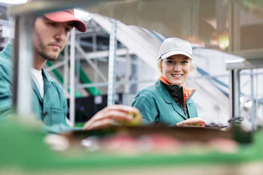 Portrait smiling female worker inspecting apples in food processing plant - Powered by Adobe