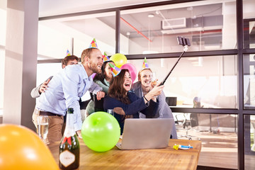 Playful business people celebrating birthday taking selfie selfie stick in conference room