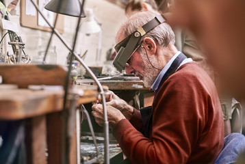 Jeweler wearing headband magnifier working in workshop