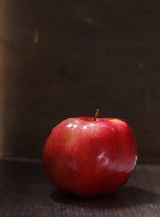 One red apple with a handle on a dark background