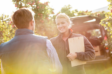 Smiling farmers talking in sunny apple orchard