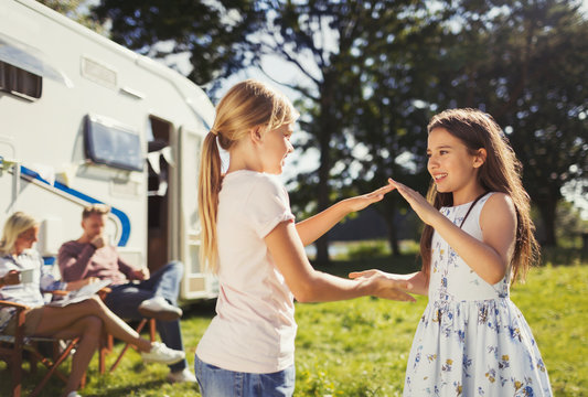 Sisters playing pat-a-cake outside sunny motor home