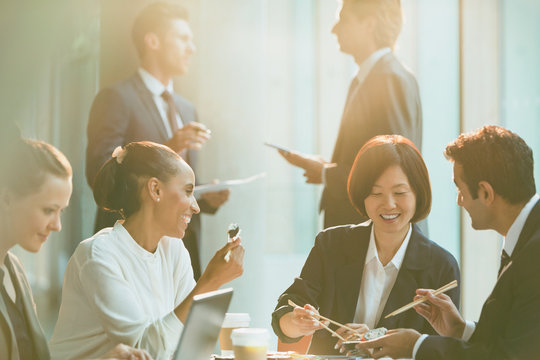 Smiling Business People Eating Lunch Chopsticks In Conference Room Meeting