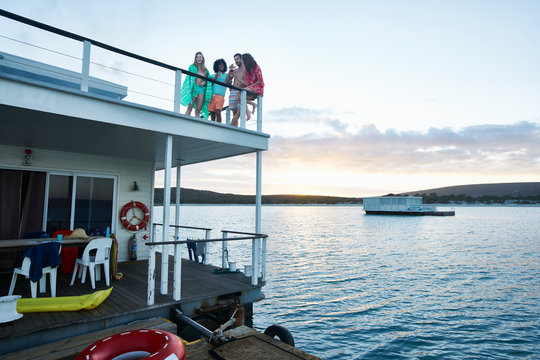 Young adult friends hanging out on deck of summer houseboat on ocean