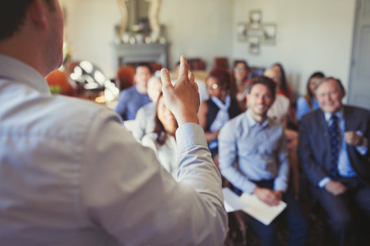 Business people in audience watching businessman leading business conference