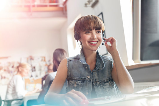 Smiling design professional using headset with microphone in office