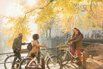 Friends with bicycles along sunny autumn canal in Amsterdam