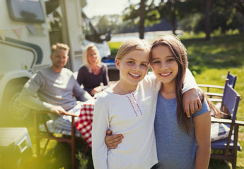 Portrait smiling sisters hugging outside sunny motor home