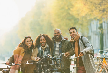 Portrait smiling friends bike riding on urban autumn street