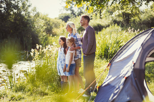 Family at sunny campsite lakeside looking away