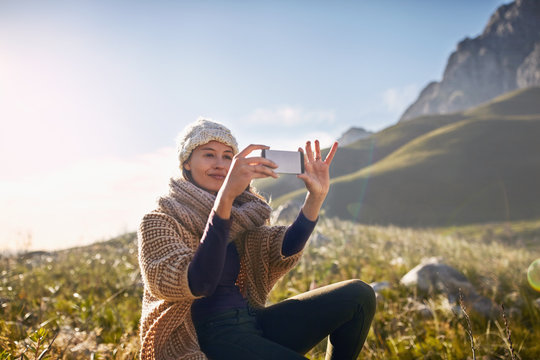 Young woman using camera phone in sunny, remote valley