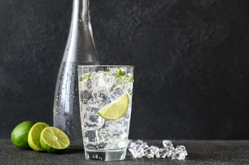 Glass of sparkling water with ice cubes and slice of lime