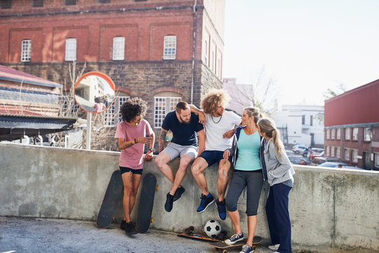 Friends with skateboards hanging out on urban summer wall
