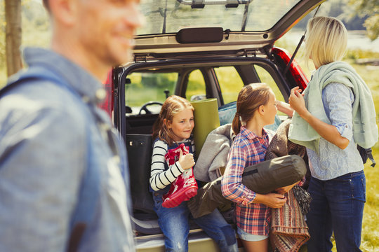 Family unloading camping equipment from car