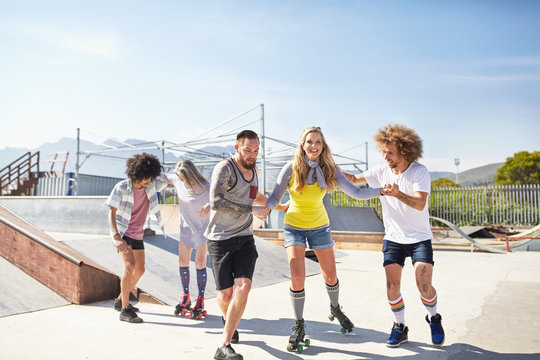Friends roller skating at sunny skate park