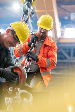 Steel workers with crane hook in factory