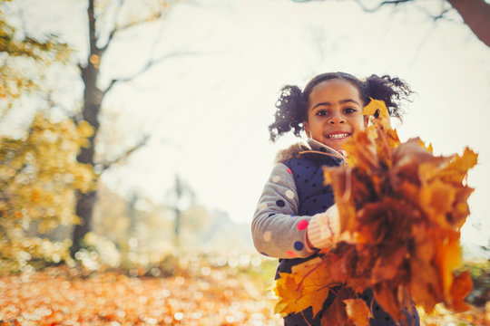 Portrait smiling girl holding autumn leaves in park