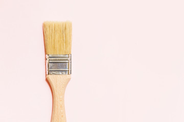 Wooden handle paintbrush isolated on soft bright pink. House renovation background.