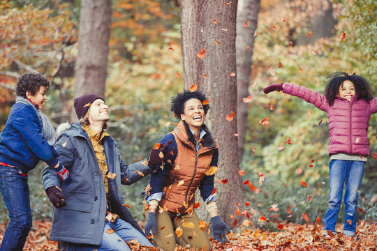 Playful young family throwing autumn leaves in woods
