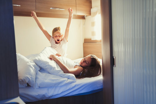 Sisters waking and stretching on bed in motor home