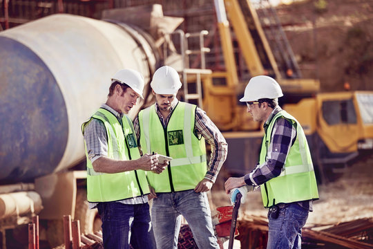 Construction workers meeting, using digital tablet at construction site