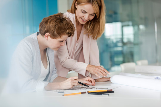 Female designers reviewing sketch drawings in conference room meeting