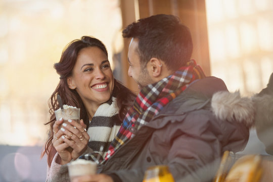 Smiling young couple drinking milkshakes at sidewalk cafe