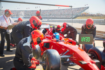 Pit crew replacing tires on formula one race car in pit lane practice session
