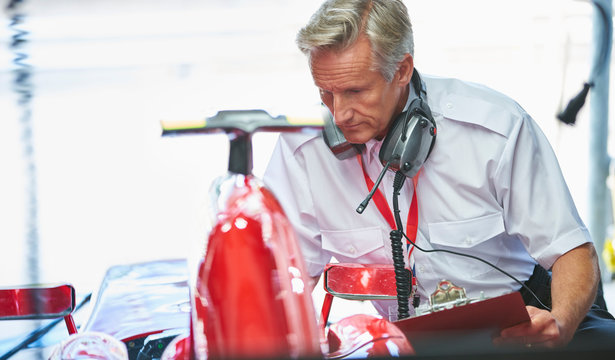 Manager with clipboard next to formula one race car
