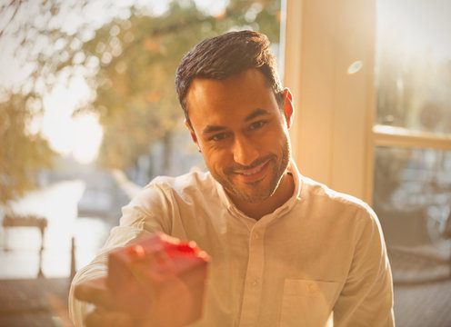 Personal Perspective Young Man Giving Gift In Sunny Cafe