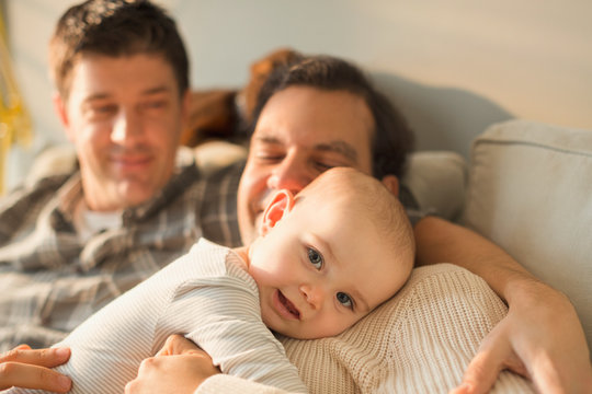 Portrait cute baby son cuddling with male gay parents