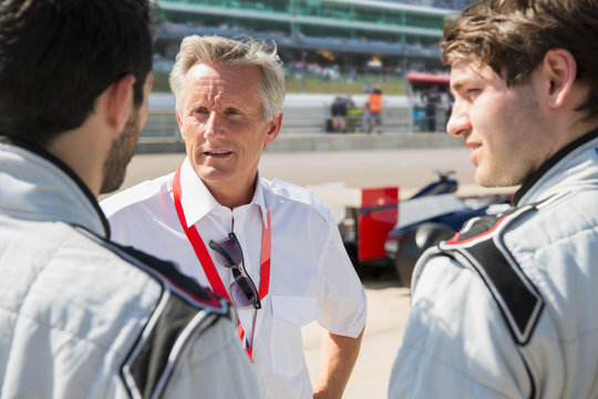 Manager talking to formula one drivers on sports track