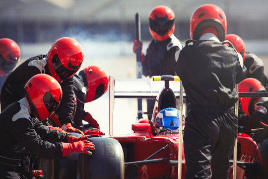 Pit crew replacing tires on formula one race car in pit lane