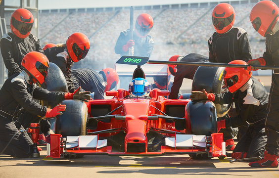 Pit Crew Working On Formula One Race Car In Pit Lane