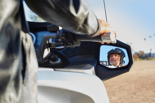 View of senior man in side-view mirror riding motorcycle