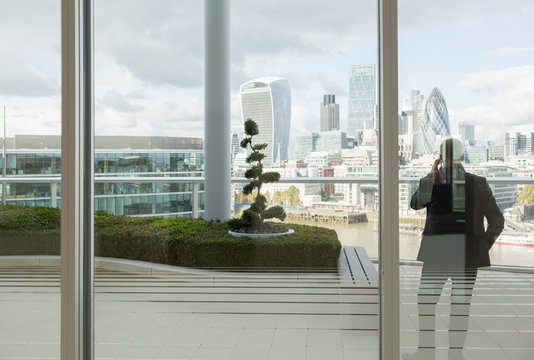 Businessman talking on cell phone on balcony urban city view, London, UK