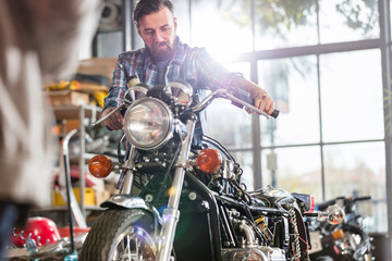 Male motorcycle mechanic working on motorcycle in workshop