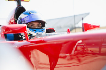 Focused formula one race car driver wearing helmet, looking away