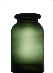 Leere, große grüne Vase/Flasche mit großer Öffnung aus transparenten Glas vor hell erleuchtetem Hintergrund