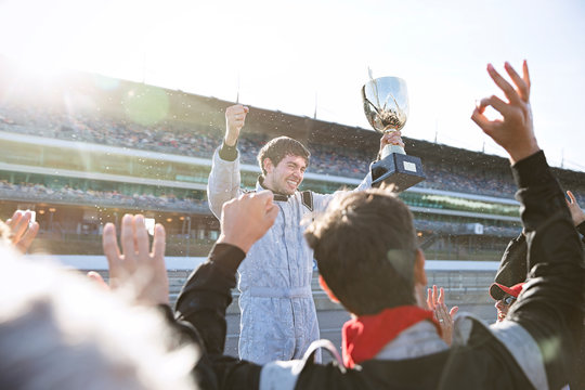 Formula one racing team cheering for driver trophy, celebrating victory on sports track