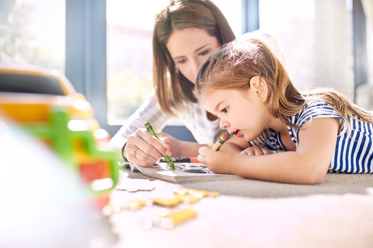 Mother and daughter coloring in coloring book with crayons
