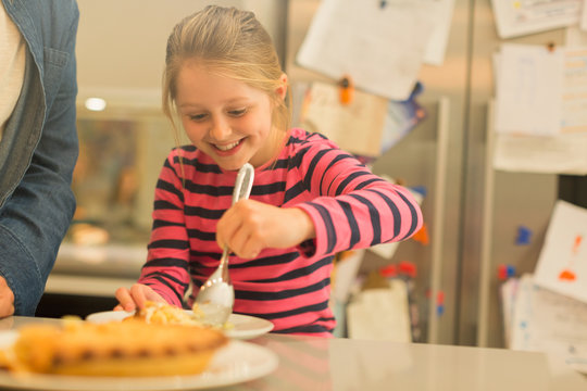 Smiling, eager girl serving pie in kitchen