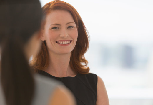 Smiling businesswoman with red hair talking to colleague