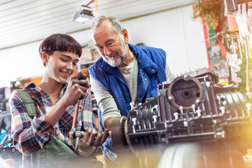 Male and female motorcycle mechanics repairing engine in workshop